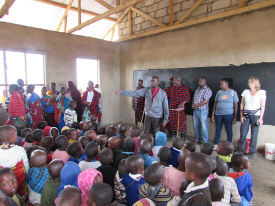 Die Dorfältesten haben sich mit uns aufgestellt, während nun auch die Frauen in den Klassenraum treten.