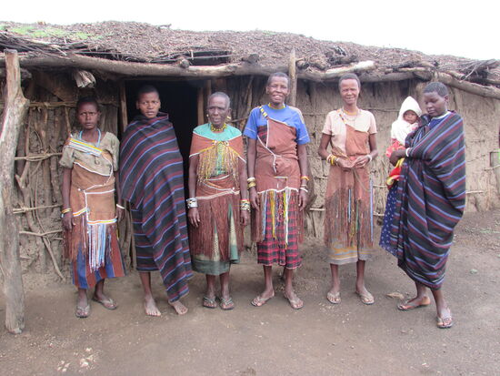 Wir werden freundlich empfangen und unser Guide sagt uns etwas zur Kleidung.
Die Frauen, welche ein Kleid aus Tierhaut tragen sind verheiratet, die anderen zwei nicht. Die Kleider aus Tierhaut haben Fransen, die reich mit Perlen geschmückt sind.