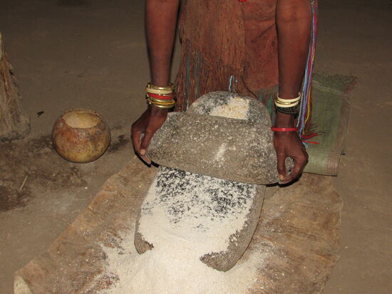 Wir werden in die Hütte gebeten und man zeigt uns bei Gesang, wie Maismehl gemahlen wird.