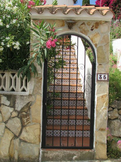 Typischer Eingang - Metalltor und die Treppenstufen mit bunter Keramik gestaltet.