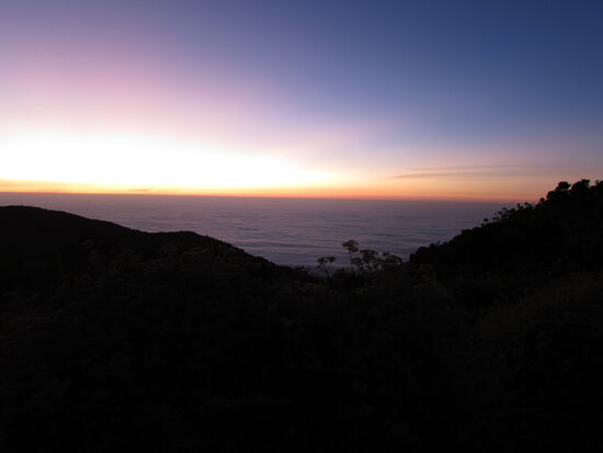 Zunächst ist es nur ein schmaler roter Streifen der über den Wolken sichtbar wird.