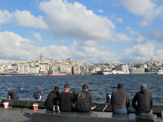 Am Bosporus sitzen unzählige Angler. In der Ferne ist auf dem Hügel der Turm zu sehen.