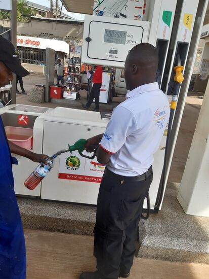 Beim Stopp an der Tankstelle sehen wir, wie einem Motorrad Fahrer der Sprit in die Flasche gefüllt wird.