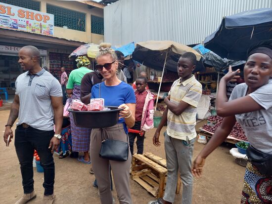 Eine Marktfrau reicht Kerstin eine Schale mit Beeren. Sie soll sie auch mal auf ihrem Kopf tragen.