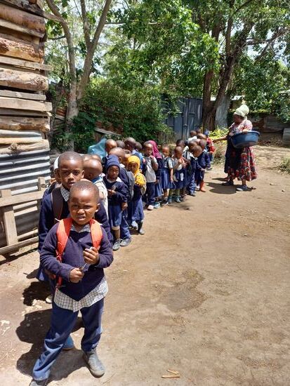 Es ist Mittagszeit- alle stehen brav in einer Reihe. Ich helfe bei der Essensausgabe.