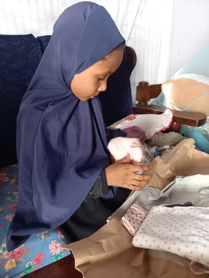 Sie packt das Geschenk ihrer Paten erwartungsvoll aus und freut sich riesig.