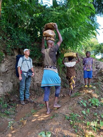Dieser Mann trägt Barfuß zwei große Steine den Berg hinauf.