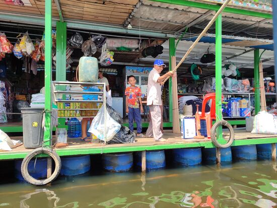 An einem schwimmenden 'Supermarkt' gab es eine halbstündige Pause. Der Mann zieht das Schiff mit der Stange zum Anleger.