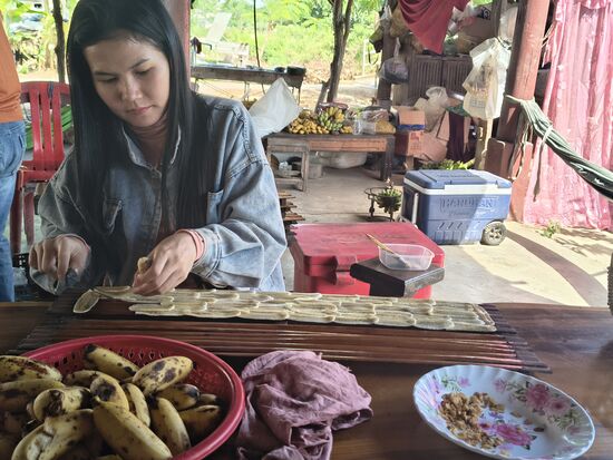 Die Bananen werden mit der Hand hauchdünn geschnitten und überlappend auf ein Bambusbrett gelegt