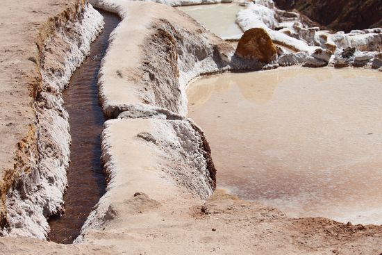 In einem etwa 15 cm breiten Kanal kommt das stark salzhaltige Wasser aus dem Berg und wird zu den Feldern geleitet.