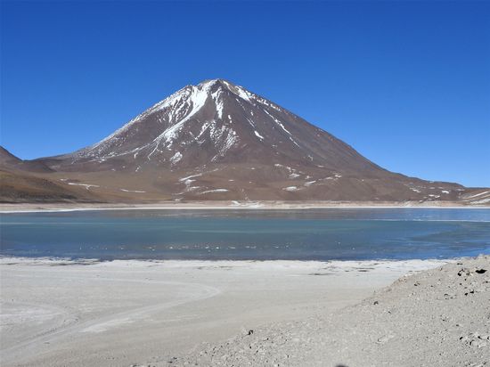 Laguna Verde - eigentlich die grüne Lagune aber da die Seeoberfläche leicht gefroren war konnte der Wind die eingelagerten Mineralien nicht vermischen und der grüne Farbton blieb aus. Der See ist neben anderen Mineralien so stark arsenhaltig dass ein Bad tödlich wäre. Hier leben auch keine Flamingos mehr. 
Im Hintergrund der inaktive Vulkan Licancabur den sich Bolivien und Chile hälftig teilen.