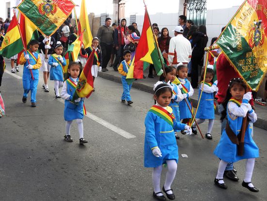Kindergartenkinder mit Fahnen die größer sind wie sie selbst.