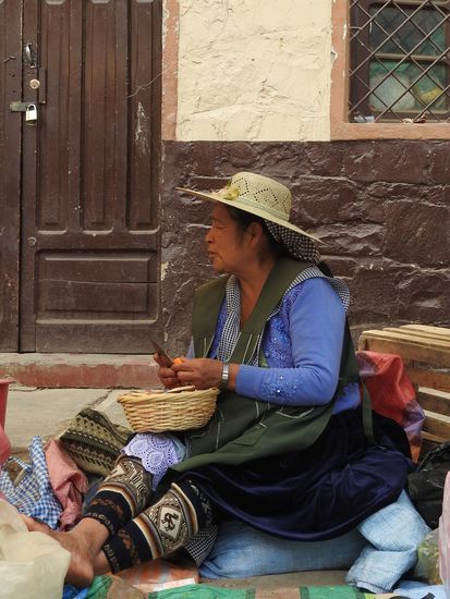 Typische Kleidung einer Indiofrau.
Eine lange bunte gestrickte Wollhose, darüber 4 immer größer werdende Spitzenunterröcke, dann kommt ein einfarbig glänzender oder bunter Faltenrock, oben ein glänzender, bestickter Pullover und darüber eine  große Trägerschürze. Auch eine ganz schmale Frau bekommt da einen gewaltigen Umfang. Am Kopf ein Strohhut oder ein dunkler Bowler.