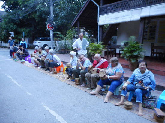 Der Abschied von Luang Prabang dann noch ein Wermutstropfen. Bewusst hatten uns dagegen entschieden, die morgentliche Prozession der Mönche anzuschauen. ( Bei Tagesanbruch verlassen die Mönche das Kloster und erhalten auf der Straße Nahrungsmittel von den Gläubigen - dafür beten die Mönche für sie mit - eine win win Situation mit langer Tradition). Das hat sich zu einem Touristenmagneten entwickelt, weil es natürlich wirklich ein sehr schöner Anblick ist, all die orange gekleideten Menschen im ersten Tageslicht. Am Abreisetag müssen wir früh zum Bus und kommen auf dem Weg dorthin genau in die Prozession. Da sitzen nun mehr Touristen als Gläubige auf Hockern entlang der Straße, unterhalten sich und dazu nochmal so viele, die nur zum fotografieren da sind - von Andacht keine Spur!
Eine gute buddhistische Übung für uns, mit dem Ärger umzugehen.
Mit dem Bus geht es dann nach Ventiane, der Hauptstadt von Laos. Wie immer auf der N 12, der Nationalstrasse,  die von der chinesischen Grenze im Norden bis zur kambodschanischen Grenze im Süden geht. Sie wurde erst in den letzten Jahren fertiggestellt und hat den Mekong als Verkehrsader abgelöst. Als Folge sind viele Menschen aus abgelegenen Bergdörfern an die Straße gezogen, weil sie sich dort bessere Lebensbedingungen erhofften. Diese Strassen-  Dörfer haben keinen Dorfplatz und keinen Tempel, beides ist die Straße. Auf den Leitplanken trocknet die Wäsche, auf Matten am Strassenrand Reis und Chili, die Kinder spielen auf der Strasse und die Haustiere ziehen dort ihre Jungen groß. Wenn man im Bus vorbeifährt, schaut man wie in das Leben der Menschen hinein. Wir hoffen, dass sich ihre Hoffnungen an die Straße erfüllen!
Ventiane als Hauptstadt lag früher einmal mitten in Laos, durch die Geschichte ist sie nun an den Rand gerutscht, auf der anderen Seite des Mekong liegt nun Thailand, ein Nachbar, der durch seine Öffnung zum Westen jetzt wirtschaftlich deutlich besser dasteht und in Laos kräftig investiert, was die Laoten nur bedingt schätzen.
Mit dem Ali Backpacker Hostel haben wir eine nette und günstige Unterkunft gleich am Mekong gefunden, die irritierenden Knaller vor dem Haus stellen sich als Luftballonbuden heraus, doch um 21.00 h sind alle Ballons geplatzt. Am nächsten Tag mieten wir uns Fahrräder und erkunden die geruhsamste Hauptstadt Südostasiens. Neben den in den Reiseführern beschriebenen Highlights finden wir gerade im "Tempel daneben" oft eine ganz ansprechende Darstellung oder etwas Besonderes. Wie überall im Land sind die alten Tempel im Indochina- Krieg oder spätestens im Vietnamkrieg zerstört worden und während der anschließenden kommunistischen Periode auch nicht wiederaufgebaut worden. So sind die jetzigen Tempel bis auf wenige Ausnahmen alle erst in den letzten 15 Jahren wiederaufgebaut worden und weisen dadurch eine gewisse Gleichartigkeit auf. Gerade dadurch hebt sich der Tempel Wat Si Sakhet  daraus hervor und es erscheint wie ein Wunder, dass er all dieser  Zerstörungswut entgangen ist. 
Gegen Abend noch eine schöne Radtour Mekong aufwärts in den Sonnenuntergang. (Wer jetzt neidisch zu werden beginnt, dems sei auch erzählt, dass mit dem Sonnenuntergang eine Armee von Mücken ausschwaermt und jede freie Körperstelle findet)
Außerhalb der Stadt, gut mit dem Linienbus 14 zu erreichen, liegt der sogenannte Buddhapark. Ein Mönch hat hier in den 50 er Jahren mit dem neuen Werkstoff Beton experimentiert und Darstellungen aus Hinduismus und Buddhismus in beeindruckender Größe geschaffen. Die Strasse dorthin ist über weite Strecken aus rotem Sand und Häuser wie Pflanzen am Strassenrand sind mit einer dicken Staubschicht bedeckt. Hier wird die mit Unterstützung Thailands geplante Sanierung der  Strasse für die Menschen ein Segen sein.