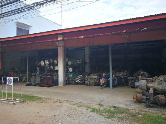 Ersatzteilhandel direkt vor meinem Hotel in Vang Vieng. Das hinter dem Mann sind sozusagen Austauschmotoren