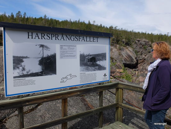 Auf der Infotafel mit alten Fotos des ehemaligen Harsprangfallets, von dem man heute kaum ein Plätschern vernimmt, erahnt man die gewaltige Wasserwucht, die jetzt oberhalb der Felsenrinne per Staudamm eingefangen und durch Turbinen in grünen Strom umgewandelt wird.