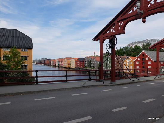 Hinterm Dom überquert man diese alte Holzbrücke und blickt von dort auf die bekannteste Ansicht von Trondheim, die alten bunt gestrichenen Lagerhäuser am Nidelva. Gleich danach kann man ins idyllische Bakklandetviertel eintauchen.