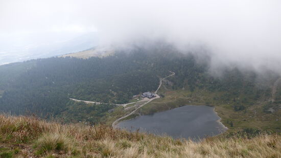 Wir umwandern den Kleinen und den großen Teich. Oben im Nebel sieht man die Hampelbaude, unten am Wasser befindet sich die Kleine Teichbaude
