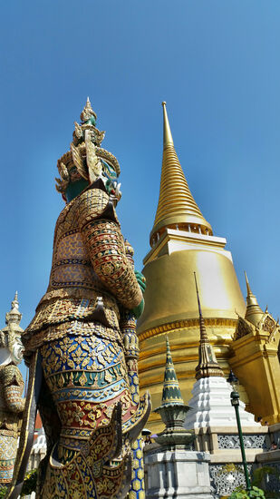 Wächterfigur und goldene Chedi im  Wat Phra Kaeo in Bangkok