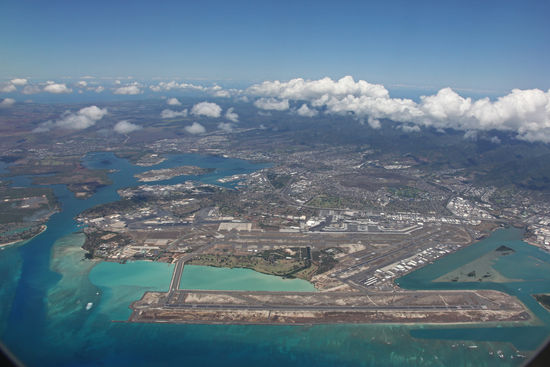 Der Daniel K. Inouye International Airport bewältigt 21 Millionen Flugpassagiere jährlich - mit steigender Tendenz. Er liegt auf der Insel Oahu. Die Bucht links ist der berühmte Pearl Harbor, rechts liegt die Stadt Honolulu.