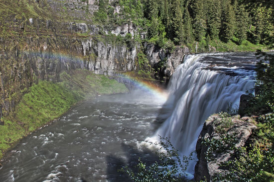 Upper Mesa Falls
Immerhin 35 Meter hoch und 61 Meter breit sind die Upper Mesa Falls. Die Tuffkante, über die das Wasser strömt, ist 1,3 Millionen Jahre alt. Nach dem Entstehen der ersten der drei Yellowstone-Calderas füllten spätere Lavaströme die Caldera auf. Diese Lavaströme wurden in der Zeit zwischen 600000 und 200000 Jahren vor unserer Zeit vom Fluss abgetragen. Immer wieder querten Lavaströme den Canyon, immer wieder wurde der Fluss abgeschnitten und musste sich immer wieder durchfressen, bis der Canyon schliesslich seine heutige Gestalt annahm.