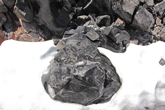Schwarzes Glas im Schnee
In höheren Regionen auf dem Big Obsidian Flow des Newberry-Kraters liegt noch etwas Schnee. Weil der schwarze Obsidian sich sehr schnell aufheizt, schmilzt er einen kleinen Hof um sich selbst.