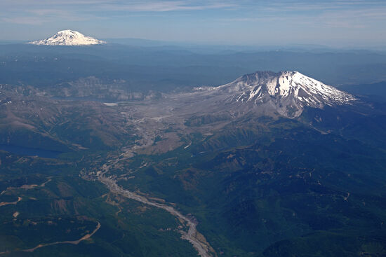 Asche über den Horizont hinaus
Hier sieht man deutlich, wie der Mt. St. Helens im Mai 1980 nach Norden hin (links) ausgebrochen ist. Ascheregen gab es bis weit nach Kanada hinein und der Osten des Bundesstaates Washington lag tagelang unter einer dichten, dunklen Wolke. Der Toutle River (im Vordergrund) nahm einen Teil der Asche auf und überschwemmte und zerstörte zahlreiche Häuser, bis er sich in den Columbia River ergoss. Für die Schifffahrt musste die Fahrrinne des Columbia River nach der Eruption neu ausgebaggert werden.