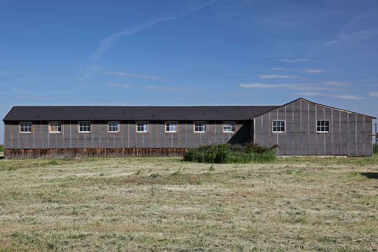 Baracken aus Dachpappe
Dieses Bild zeigt die Ecke des Blocks 22. Alle 35 Wohnblocks von Minidoka bestanden aus je 12 Barracken, einer Kantine, einem Raum für Freizeitaktivitäten und einem zentralen, H-förmigem Bau mit Bädern, Duschen und Waschraum. Die Internierten hatten nicht viel Privatsphäre, denn die Innenwände waren auch aus Dachpappe. Man hörte, wenn der Nachbar sein Zimmer fegte. Die äussere Wand wurde von den Internierten nach Innen hin mit Wachs und Stofffetzen abgedichtet, so dass im Sommer kein Sand und im Winter keine Kälte durch die häufigen Stürme hereingeweht werden konnte.
