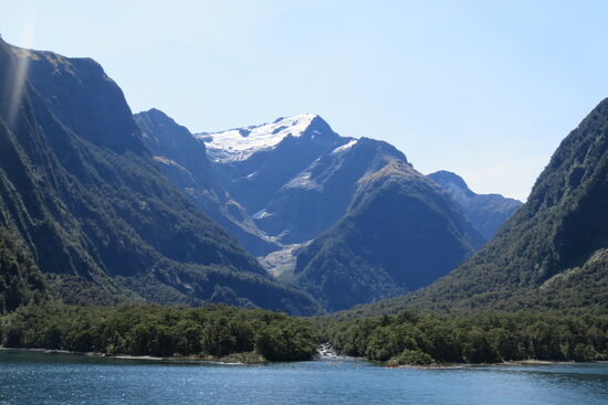 Am Ufer Regenwald, auf den Bergen die mit Schnee und Eis bedeckten Gletscher.