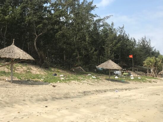Unter der roten Staatsflagge verschmutzter Strand.