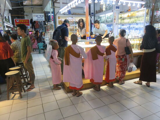 Junge Bettelmönche, vielfach noch Kinder, sind auf und um den Markt mit großen Gefäßen für Sach- und Finanzspenden von den Händlern unterwegs.