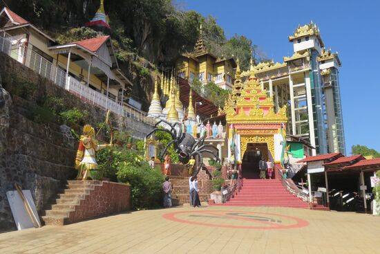 Zur Höhle führen überdachte Treppen. Wir kommen mit dem Auto. Vor dem Betreten der Höhle müssen die Schuhe abgelegt werden. Dann geht es mit dem Lift in den Glastürmen zum Eingang der Höhle. Links sind die Riesenspinne, der Prinz, mit Pfeil und Bogen bewaffnet und die sieben Schwestern zu sehen.