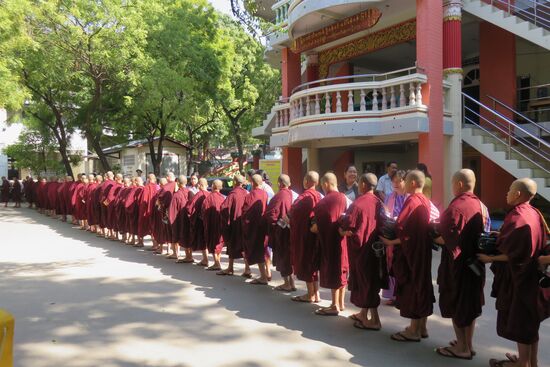 Junge Mönche im Mya Sat Kyar Kloster in Sagain stellen sich hintereinander an, um ihr Mittagessen von Spendern entgegen zu nehmen. .