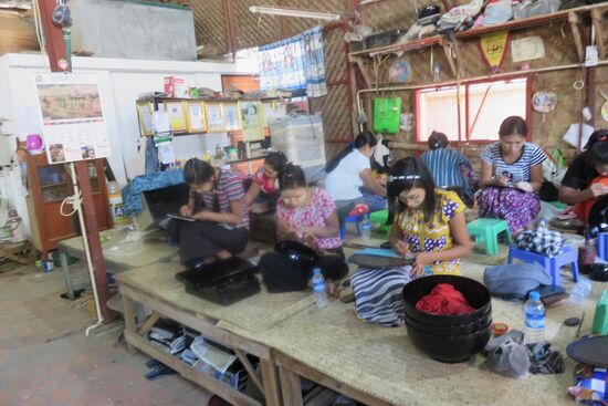 Frauen gravieren die traditionellen Muster der Holzpagoden auf die Oberflächen, um sie dann mit Farbpulver farblich zu gestalten.