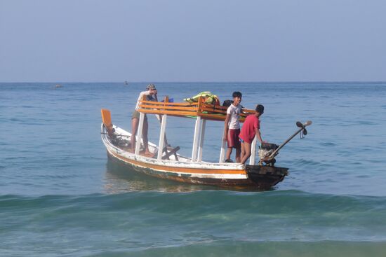 Unser Schnorchel-Abenteuer.  Nach dem Frühstück werden wir von dem Fischboot abgeholt.  Papa und seine zwei Jungs sind die Crew.  Das Boot sieht weniger vertrauenswürdig aus, aber wir begeben uns hinein und werden eine Stunde lang zur vorgelagerten Perleninsel getuckert. Noch sind  kaum Wellen zu spüren, sodass ich die Fahrt recht gut überstehe. Kurz bevor wir die Insel erreichen, ankert das Boot, wir setzen unsere Schnorchelmasken auf und begeben uns ins Wasser, etwas mühsam, sodass ich erst einmal Abstand vom Schnorcheln nehme, letztendlich mich dann doch von Siegmund überzeugen lasse. Gott sei Dank, denn die Unterwasserwelt birgt farbenfrohe und große Fischschwärme sowie auch vielfach farbige Korallen. Der Wiedereinstieg ins Boot gestaltet sich schwieriger, weil Wellen aufkommen und das Boot schwer zu halten ist. Endlich haben wir es geschafft, und wir tuckern zurück, allerdings bei recht hohem Wellengang.