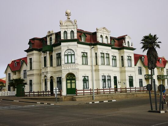 Das Hohenzollernhaus mit üppigem Stuckdekor und dem Atlas als Giebelfigur. Gilt als verspieltestes Kolonialhaus Namibias. Das Haus war mit seiner Fertigstellung 1906 das erste Hotel am Platz.