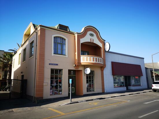 Seit mehr als 110 Jahren gibt es die Adler Apotheke in der Sam Nujuma, bis 2001 Kaiser Wilhelm-Straße. Der Apotheker Emil Kiewitt eröffnete das Geschäft 1909 und musste sich dafür die Genehmigung im deutschen Kaiserreich einholen. So musste die Apotheke nach damaligem deutschem Standard einen Keller vorweisen, den es heute noch gibt, was für die Gebäude in der Stadt sehr selten ist. Herr Kriewitt übergab das Geschäft 1929 an den Apotheker Böhlke, der es bis 1978 betrieb und dann an Frau Lohmann verkaufte, die den Laden umfassend renovierte und einen Großteil der Innenausstattung an das hiesige Museum übergab. Heute ist Frau Huber Chefin der Apotheke und trägt stolz den weißen Apothekerkittel. Inzwischen werden die Medikamente auch mit dem PC erfasst.