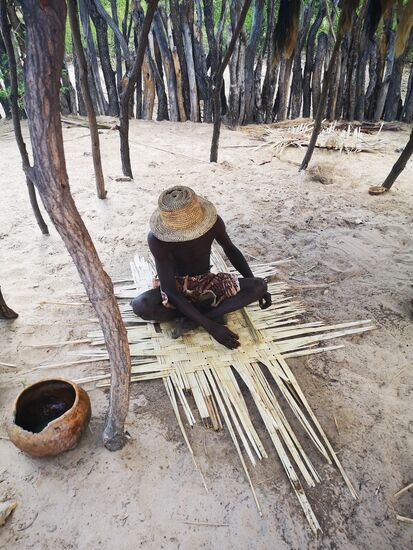 Die Alten zeigen den Jungen die Herstellung der Schlafmatten.