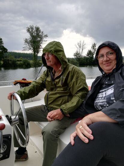 und auch Nobby steuert das Boot unter Beihilfe eines Regenschutzes - hier sei noch zu erwähnen, dass der Sonnenschirm auf dem Oberdeck als Regenschirm benutzt wurde. So weit, so gut. Leider hat der Wind etwas aufgefrischt und den Schirm mit einer kräftigen Böe in die Luft geschleudert und ins Wasser geschmissen....Böser Wind ! Nobby machte reaktionsschnell eine scharfe Linkskurve, um den Schirm noch zu retten - vergeblich, schon in der Petit Saône verschwunden.....