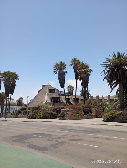 Mit einem Strohdachhaus ! Im dortigen Garten sehe ich zwei Arbeiter beim Rasenmähen und Blumengießen. Sie grüßen mich von sich aus freundlich und wünschen einen guten Rest des Tages