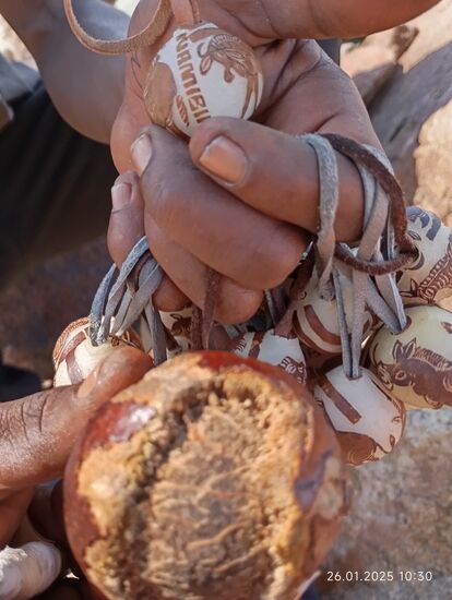 unten zeigt er mir die ursprüngliche Größe der Nuss. Deren Schale dient dem Verzehr durch seine Familie, in den Kern zieht er ein festes Band aus Leder und schnitzt dann in etwa einer Stunde die Bilder darauf. So bereitet er viele Kugeln vor und versucht sie dann, auf der Straße an Touristen zu verkaufen.