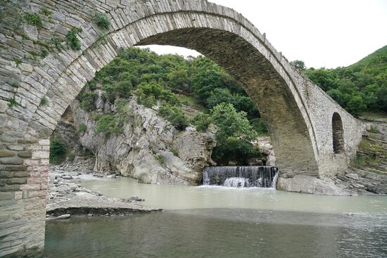 eine geländerlose, osmanische Steinbogenbrücke, über die der Wg zum Pool führt