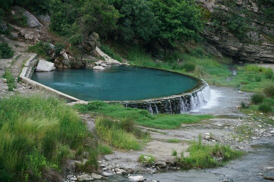 ein kreisrunder, mit groben Flussbettsteinen eingefasster Pool lädt uns ein