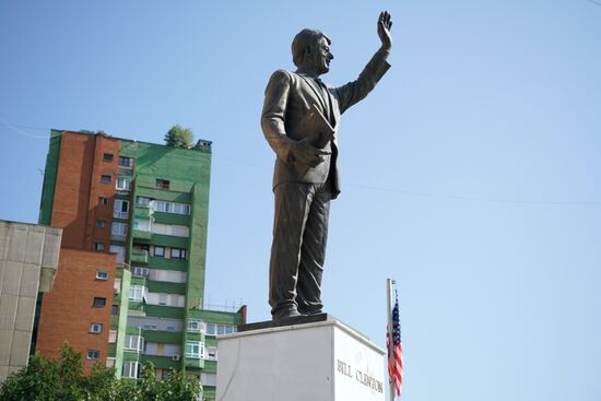 unten an der Straßenkreuzung winkt Bill Clinton den Kosovaren zu