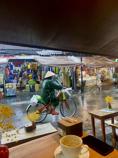 es schüttet und die vietnamesischen Straßenverkäufer erkennen sofort die richtige Verkaufsstrategie und bieten Regencapes und Regenschirme an