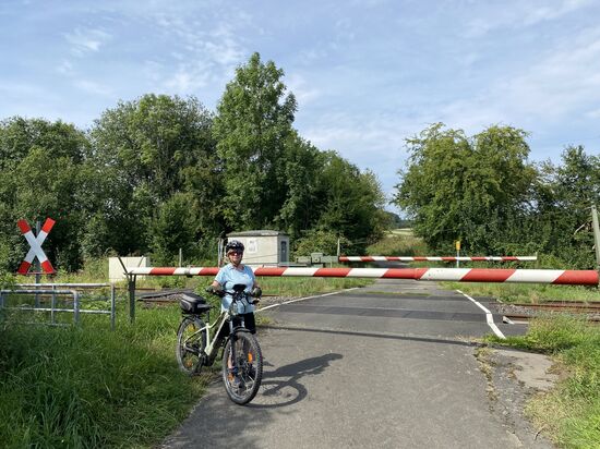Bahnübergang auf dem Feldweg. Kurz danach hört die Teerstrasse auf und wird zum Feldweg.