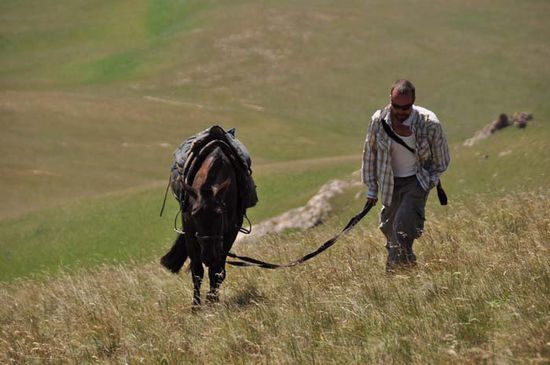 John is walking his horse to the peak of a mountain - or should  I say: the horse is walking his John ??