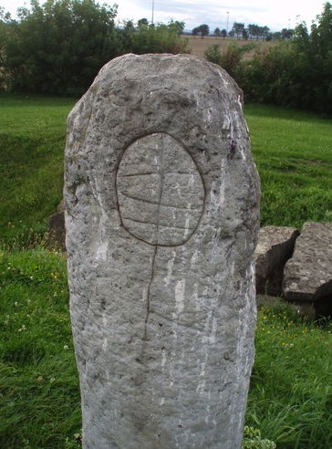 Die Einritzungen stellen das Gesicht der Göttin dar, darunter befindet sich eine Axt als Symbol der Männlichkeit. Die Seiten des Menhirs sind sehr glatt, was darauf schließen lässt, dass der Stein sehr viel berührt wurde, wahrscheinlich während eines Rituals.