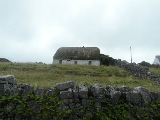 Typisch für die Aran Islands: Ein weißes Häuschen mit Reetdach, drumherum Steinmauern