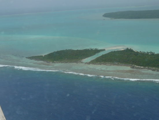 Aitutaki von oben, oder zumindest zwei Motus. Die Hauptinsel ist teilweise im Hintergrund zu sehen.